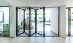 Black-framed aluminium bifold doors partially open, revealing a contemporary courtyard with pool.