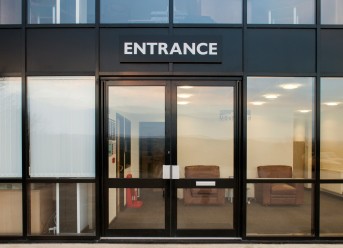Shopline aluminium shopfront doors with large glazed panels at a commercial building entrance.