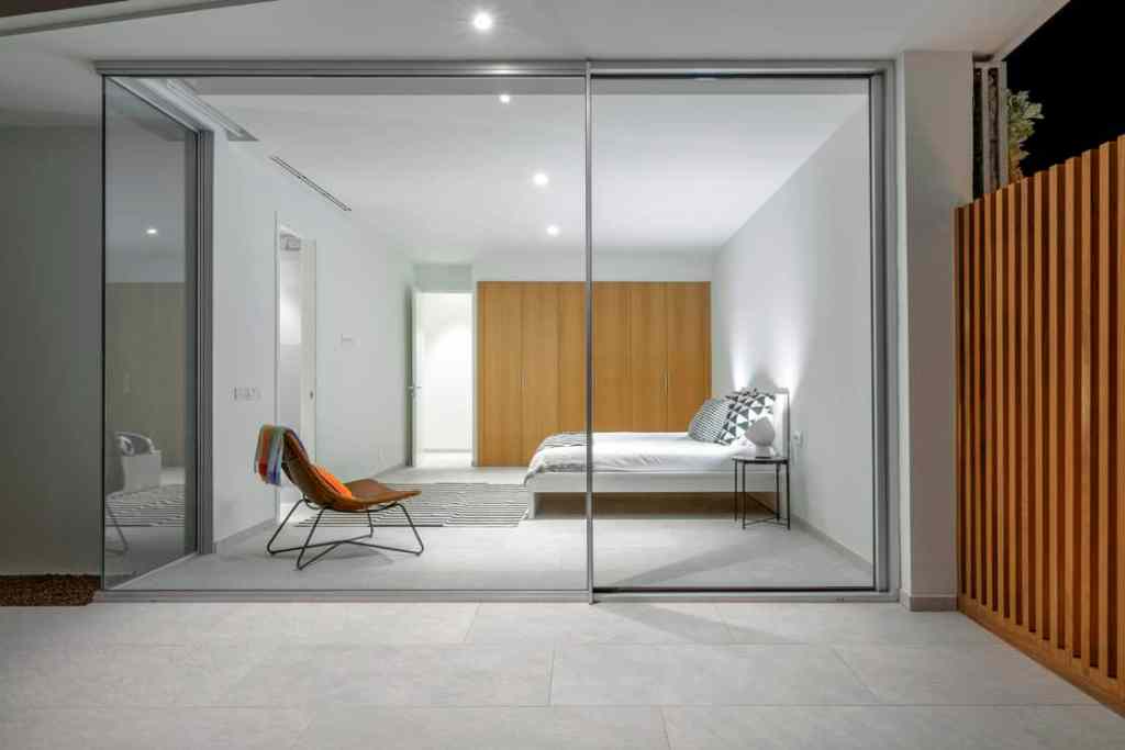 Modern bedroom with oversized sliding glass doors and minimalist decor.