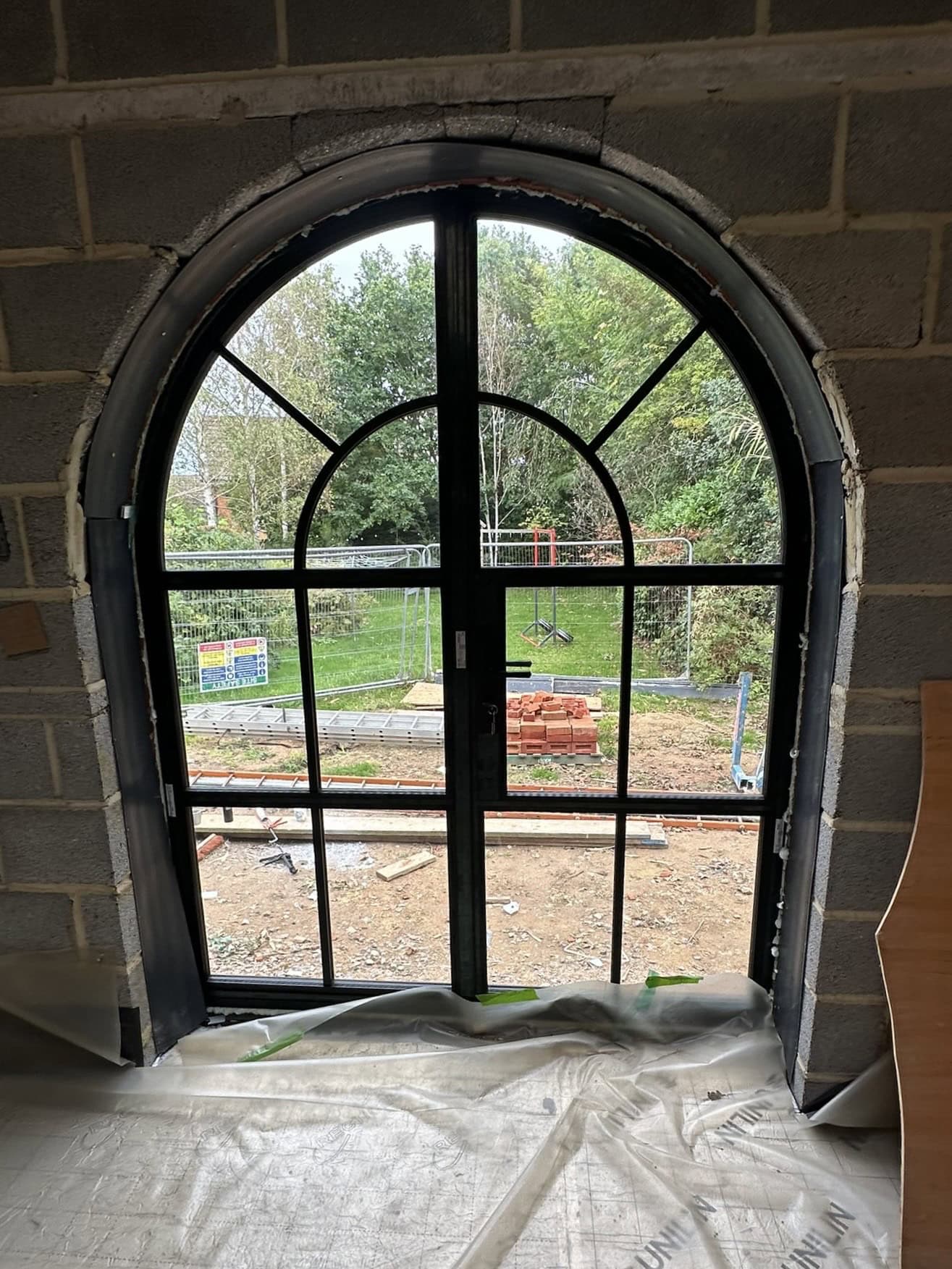 Aluminium arched window with black frame and decorative grid for stylish homes.